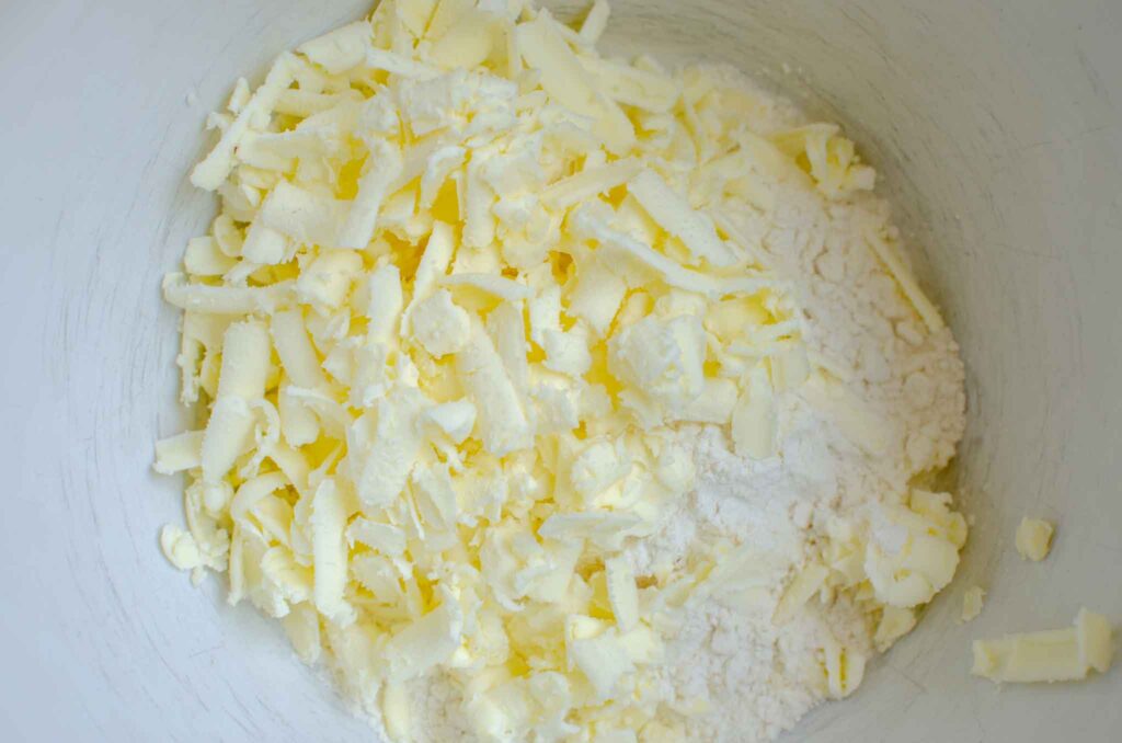 Grated butter in a bowl with dry ingredients for sourdough pie crust