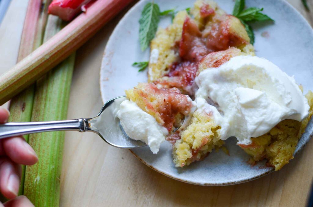 Eating a bite of rhubarb spoon cake with whipped topping