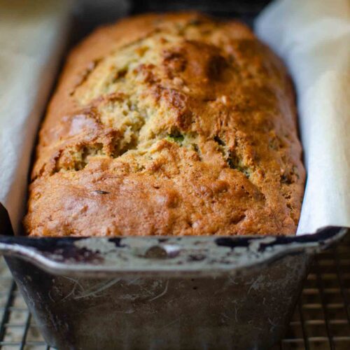 sourdough zucchini bread in parchment paper lined metal loaf pan