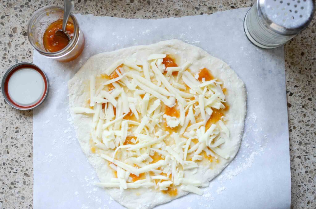 shredded mozzarella cheese on pizza dough