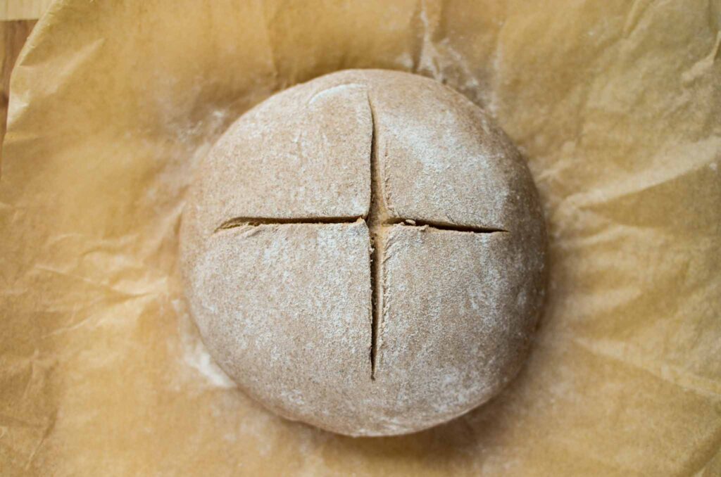 scoring the top of the dough in the shape of a cross