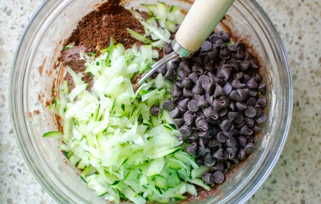 Adding grated zucchini and chocolate chips in bowl