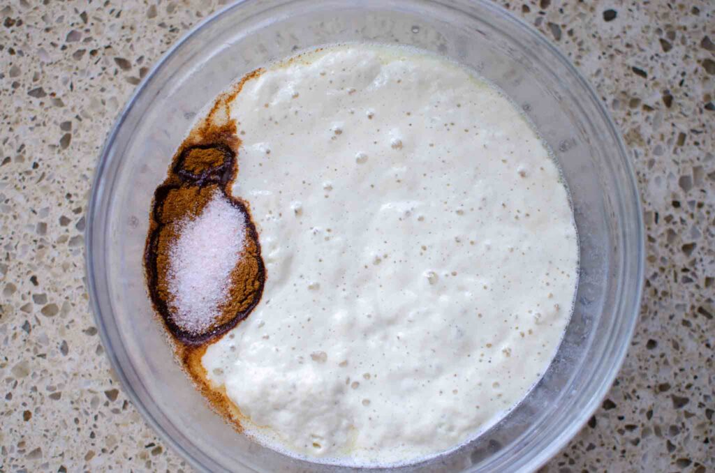 sourdough cinnamon raisin English muffin dough ingredients in a large glass bowl