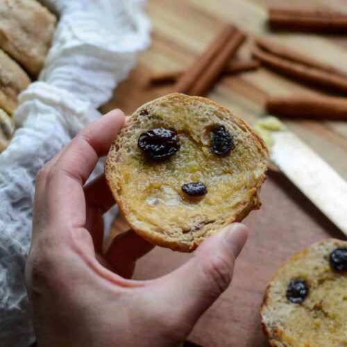 holding a sourdough cinnamon raisin English muffin sliced in half