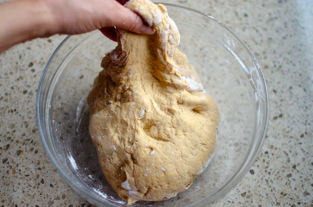 Stretching the dough that's in a glass bowl upward