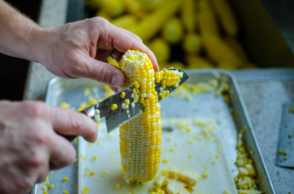 Cutting blanched corn kernels off of a cob using a sharp knife