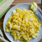 a plate of sweet corn kernels with a corn cob next to the plate