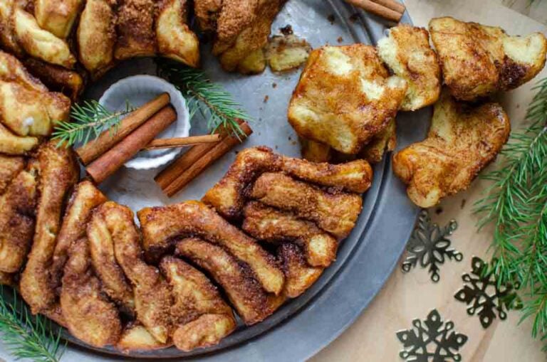 cinnamon and sugar pull apart bread on a tray qith cinnamon sticks and greenery