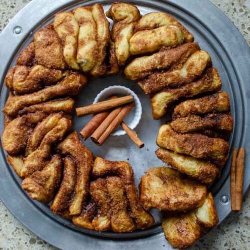 sourdough cinnamon and sugar pull apart bread on metal serving platter with cinnamon sticks