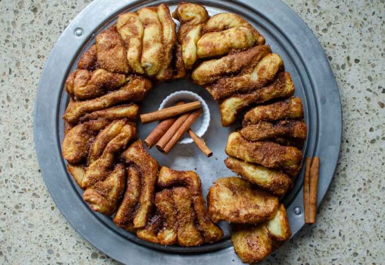 sourdough cinnamon and sugar pull apart bread on metal serving platter with cinnamon sticks