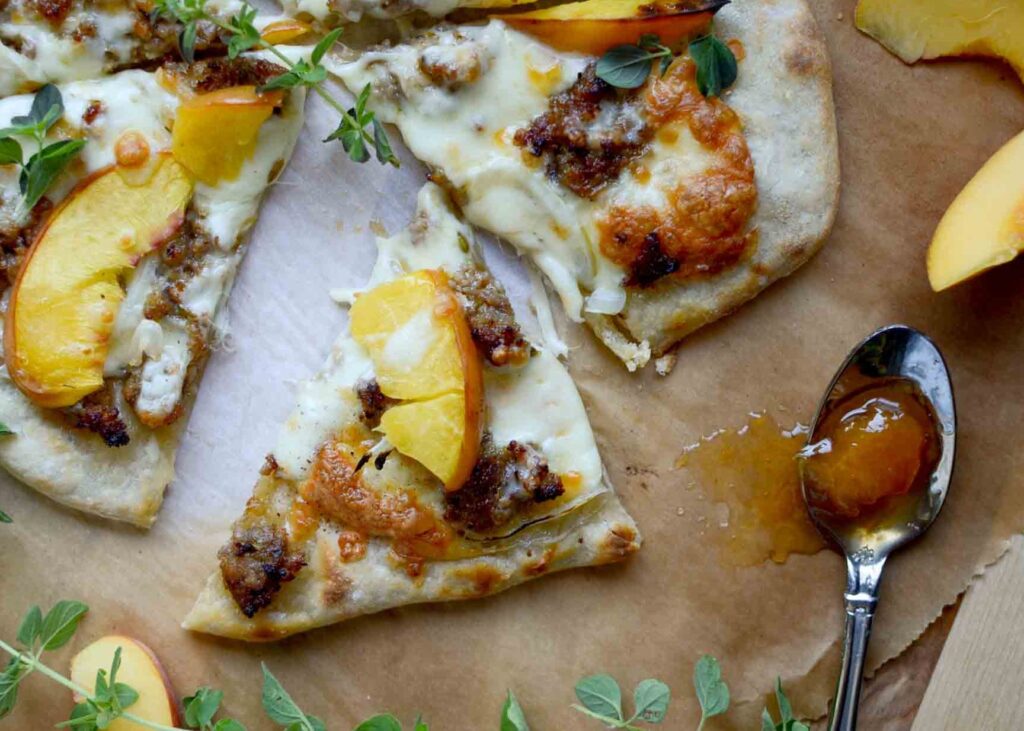 a slice of Italian sausage and peach pizza