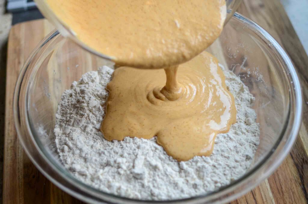 pouring wet ingredients over butter mixture in glass bowl