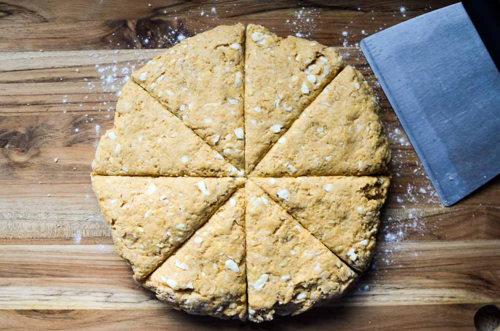 sourdough pumpkin scone dough in a round disc, cut into wedges