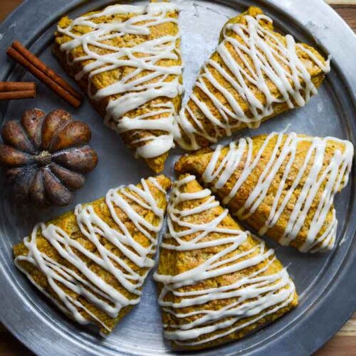 sourdough pumpkin scones on metal tray with cinnamon stick and pumpkin