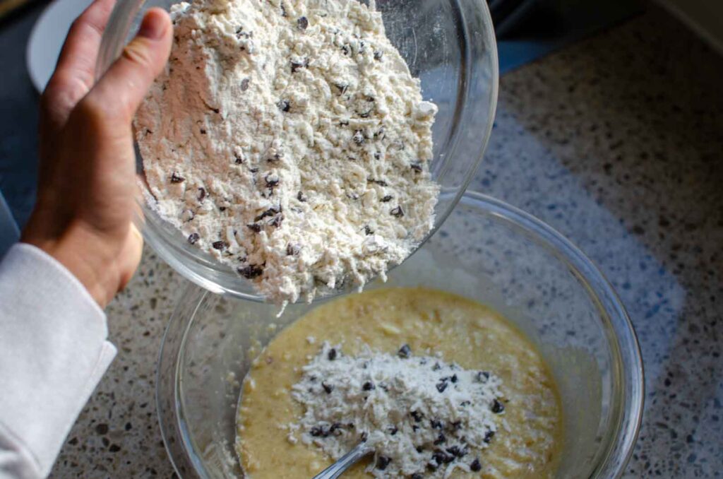 Adding the dry ingredients to wet ingredients for sourdough banana coconut chocolate chip muffins