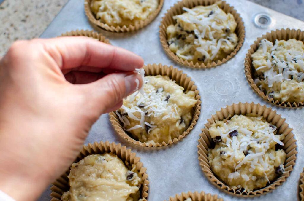 sprinkling shredded coconut over sourdough banana coconut chocolate chip muffins