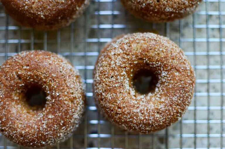 cinnamon and sugar-covered sourdough apple cider donuts on wire rack