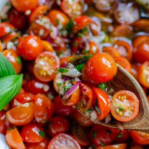 marinated tomatoes served with a wooden spoon.