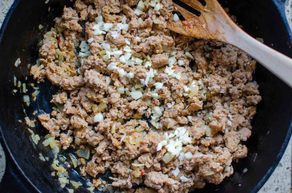 Brown Italian sausage, onion, and minced garlic in pan