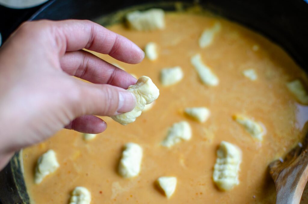 dropping uncooked gnocchi into the sauce