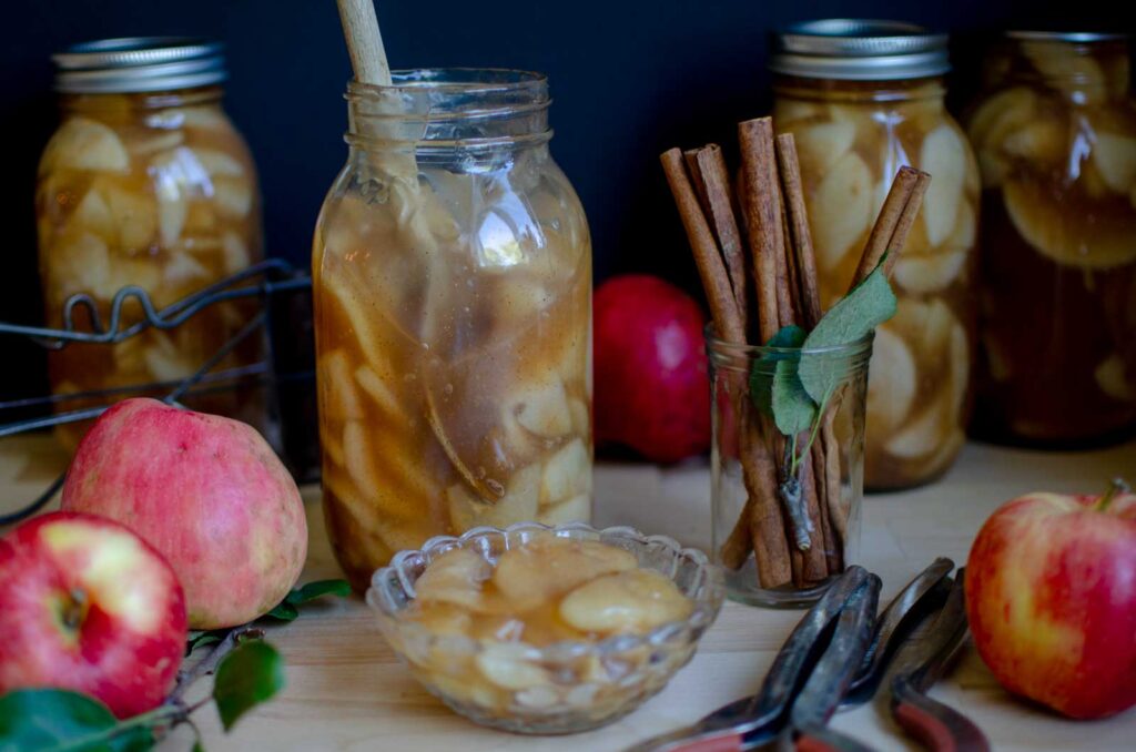 a jar of apple pie filling and a small dish with apples