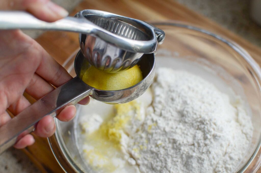 juicing a lemon into a bowl with flour and other ingredients.