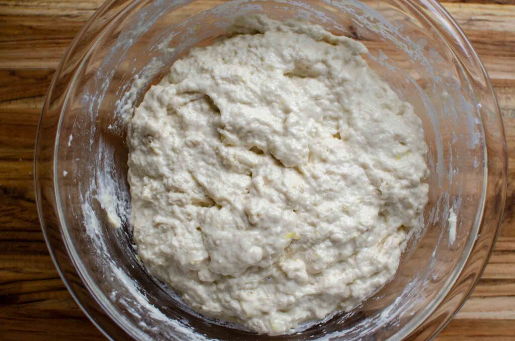 a glass bowl with mixed sourdough lemon focaccia bread ingredients