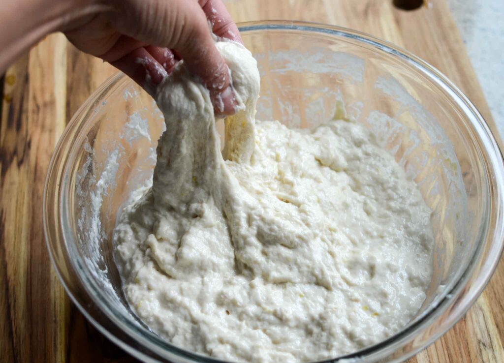 stretching sourdough lemon focaccia dough in glass bowl