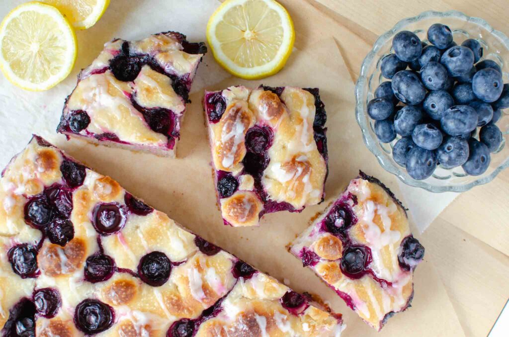 cut pieces of sourdough lemon blueberry focaccia bread with a small dish a blueberries next to it. 