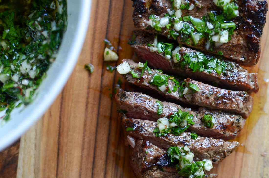 a sliced steak with chimichurri sauce