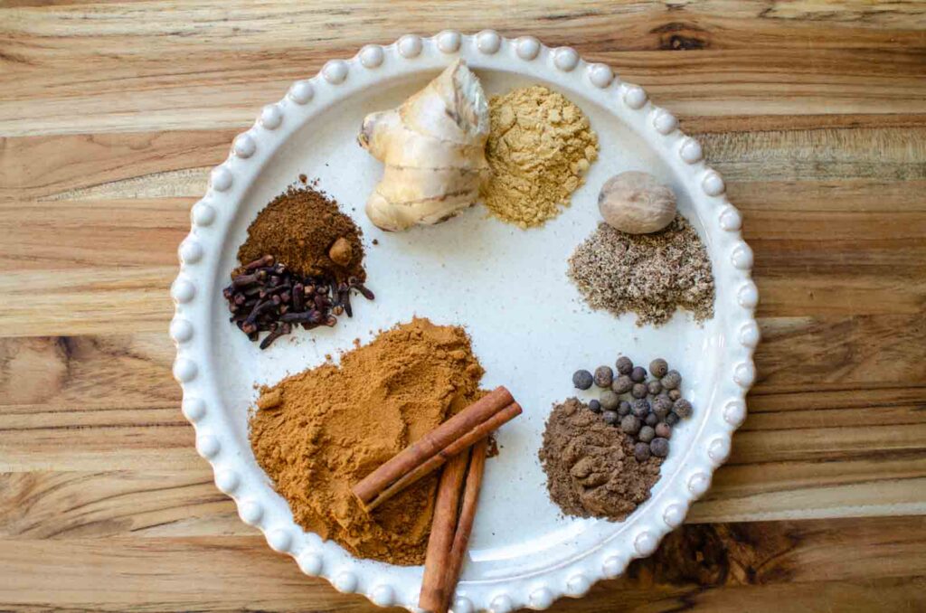 A plate full of the individual ground and whole spices that make up pumpkin pie spice.