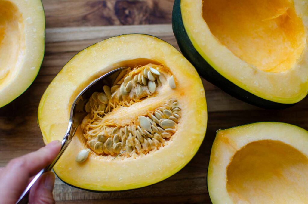 scooping seeds out of acorn squash half