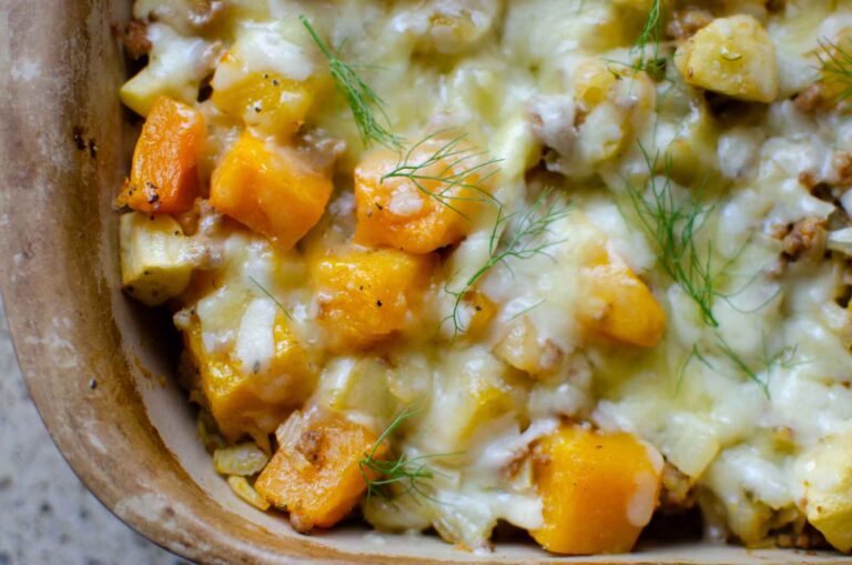 butternut squash casserole with cheesy topping in stone baking dish