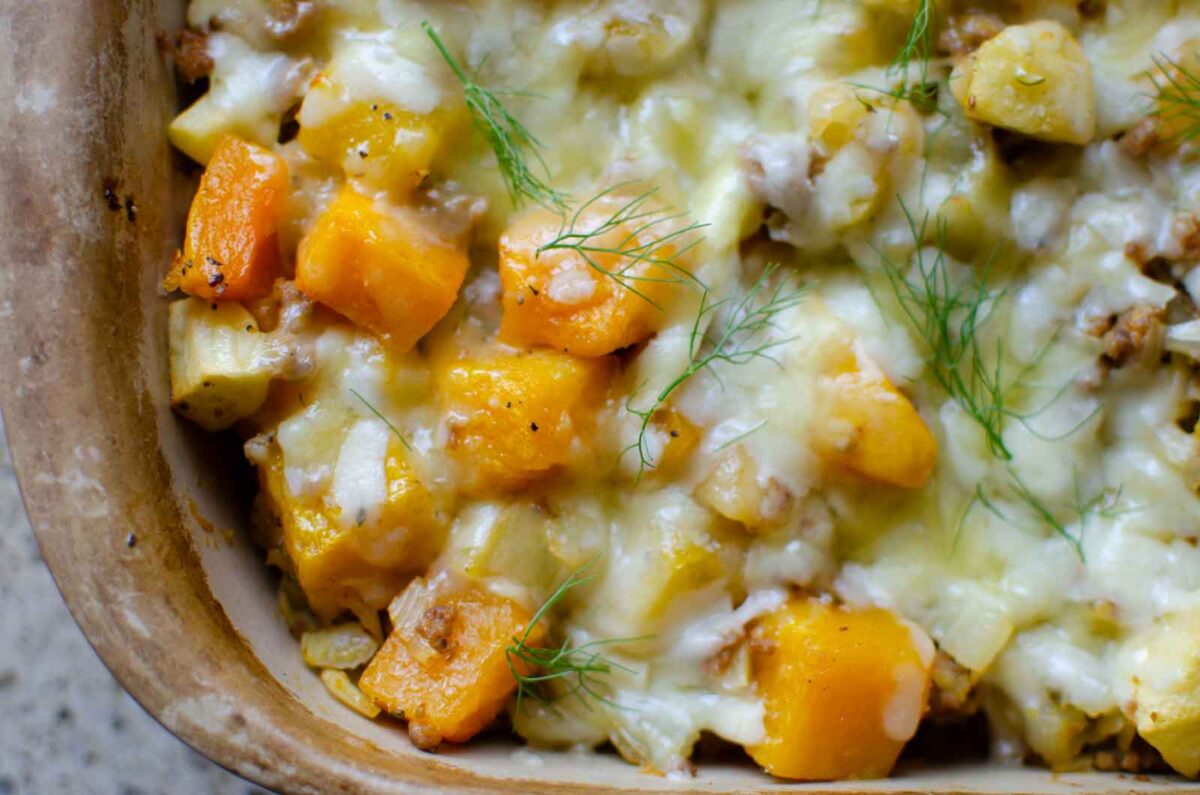 butternut squash casserole with cheesy topping in stone baking dish