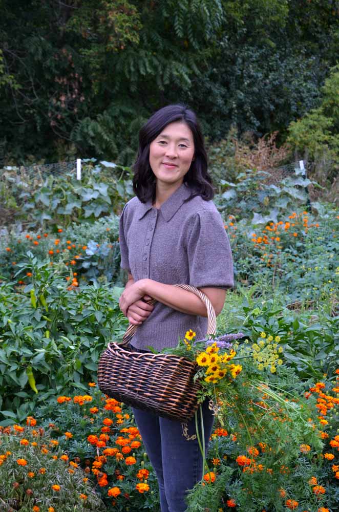 a woman in a garden holding a basket of flowers