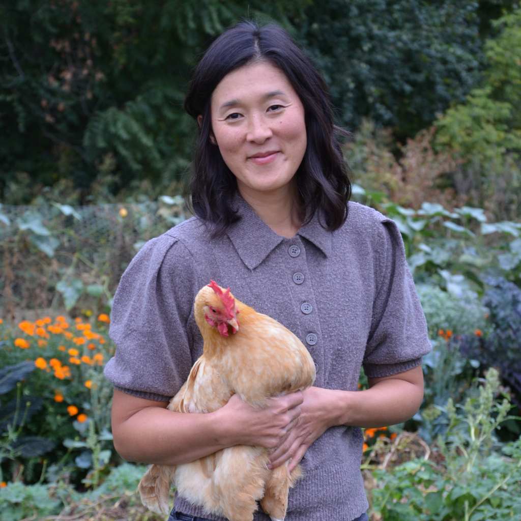 woman holding a chicken in a garden