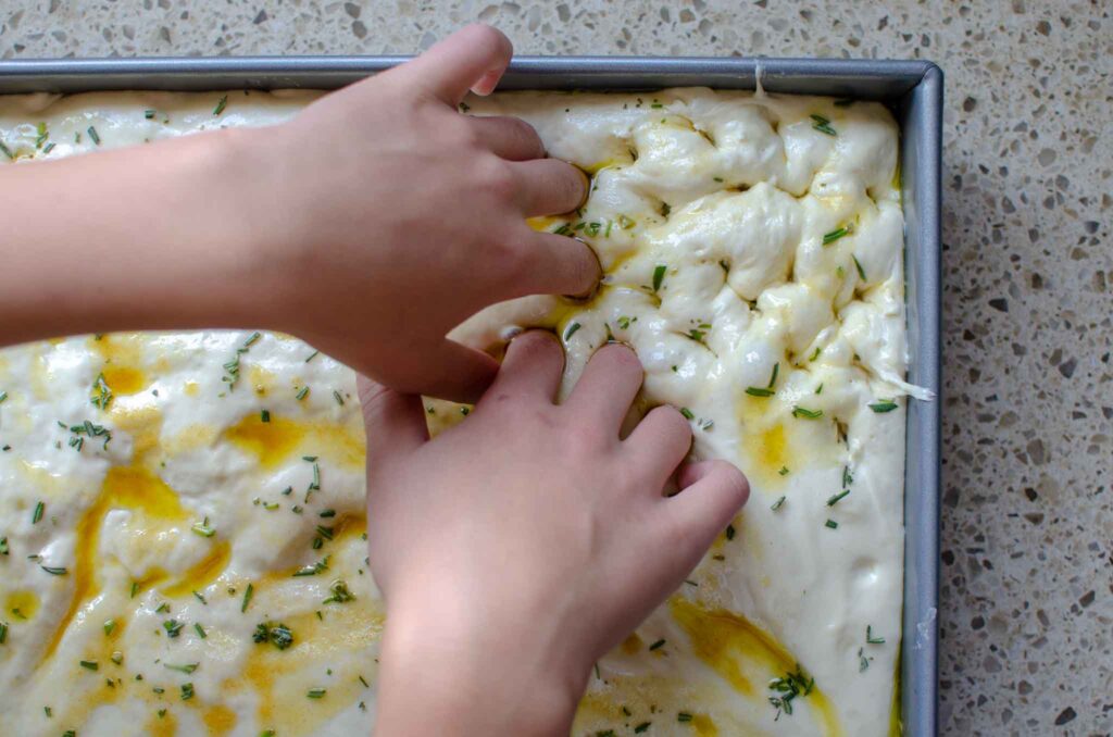 dimpling sourdough discard focaccia dough in pan