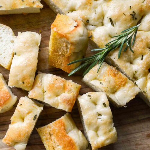 sourdough discard focaccia bread cut into pieces with a sprig of rosemary