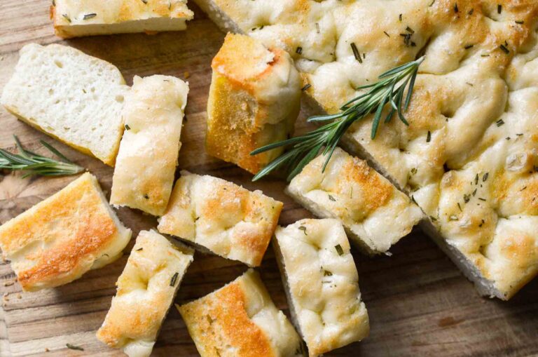 sourdough discard focaccia bread cut into pieces with a sprig of rosemary