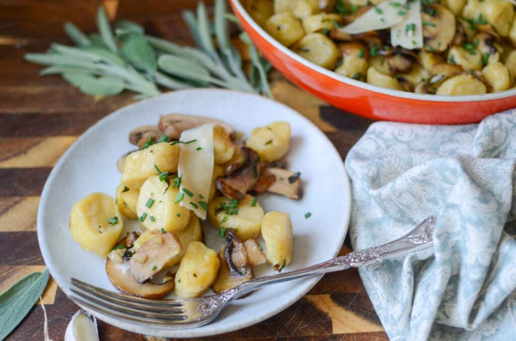 a plate of ricotta gnocchi with mushrooms and garlic sage butter sauce