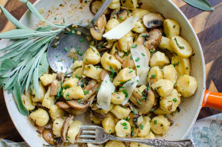 ricotta gnocchi with mushrooms and sage garlic butter sauce in large fry pan. A bundle of sage off to the side.