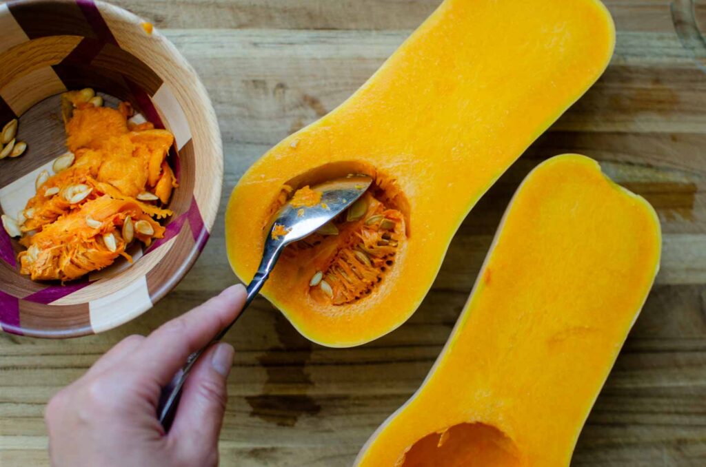 scooping seeds from butternut squash with a spoon