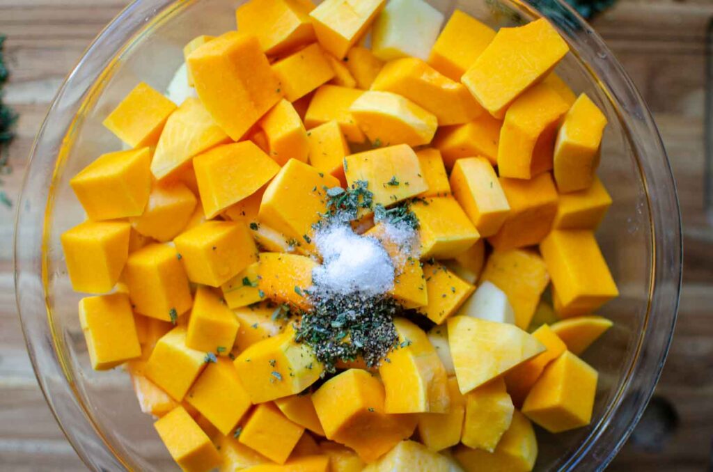 cubed butternut squash in a large bowl with seasonings