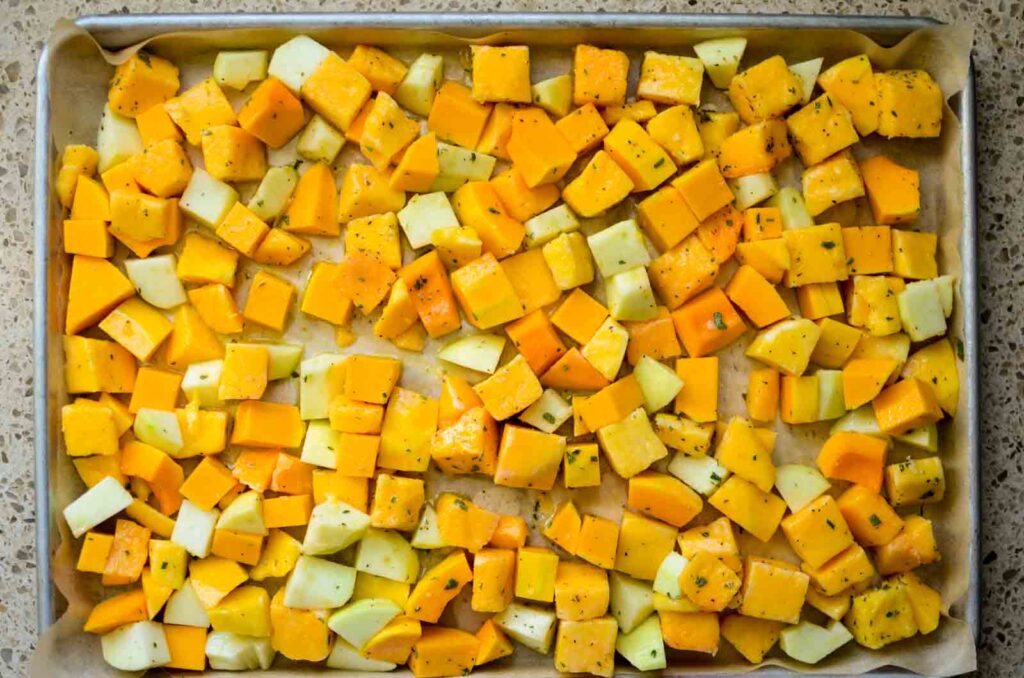 cubed butternut squash on a parchment lined baking sheet