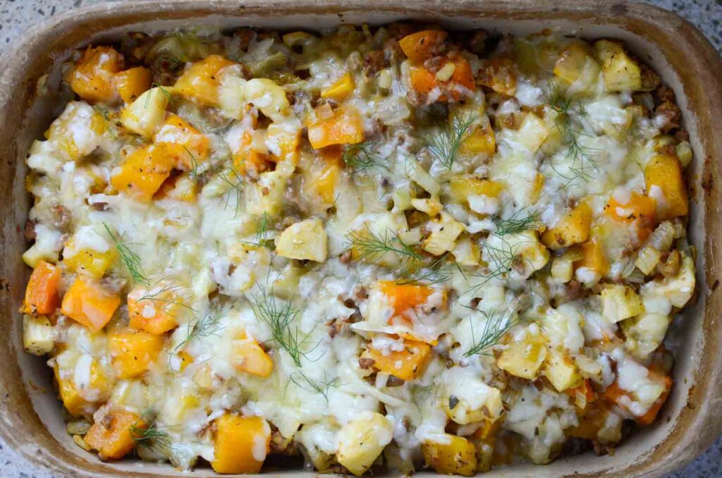 Butternut squash casserole in stoneware with cheesy topping