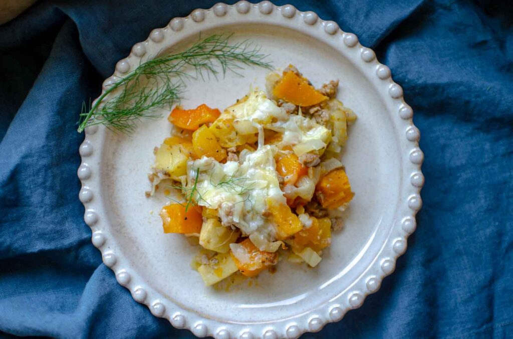 butternut squash casserole on plate which is on a blue napkin 