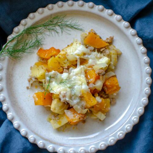 butternut squash casserole on plate which is on a blue napkin