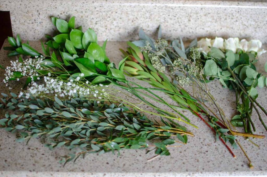 a variety of flowers and greenery on a counter