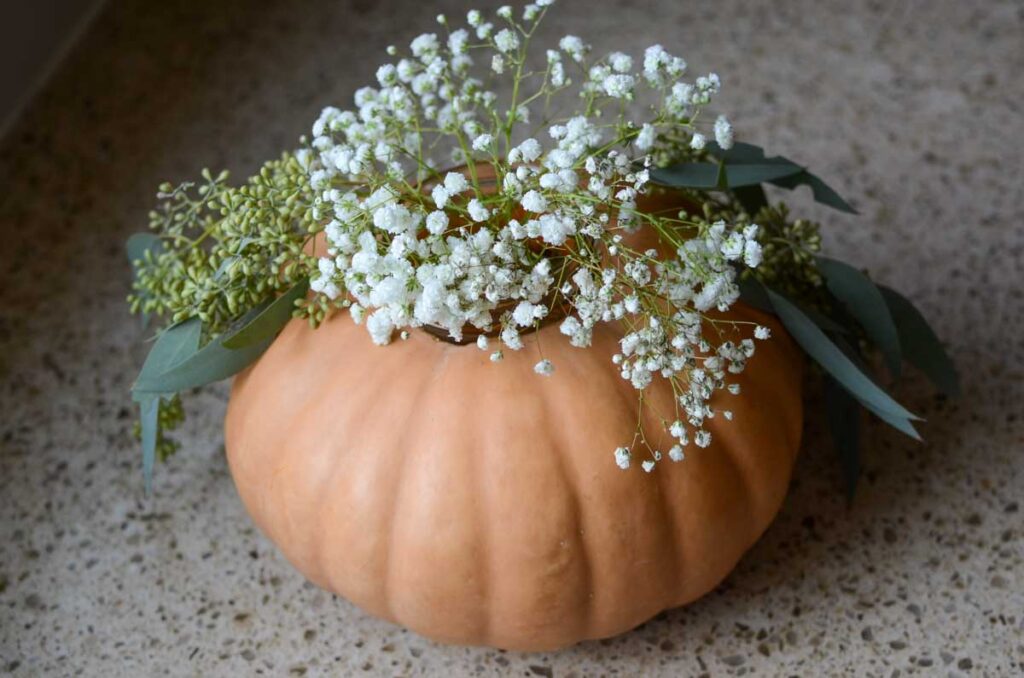 baby's breath and eucalyptus in a mason jar in a pumpkin