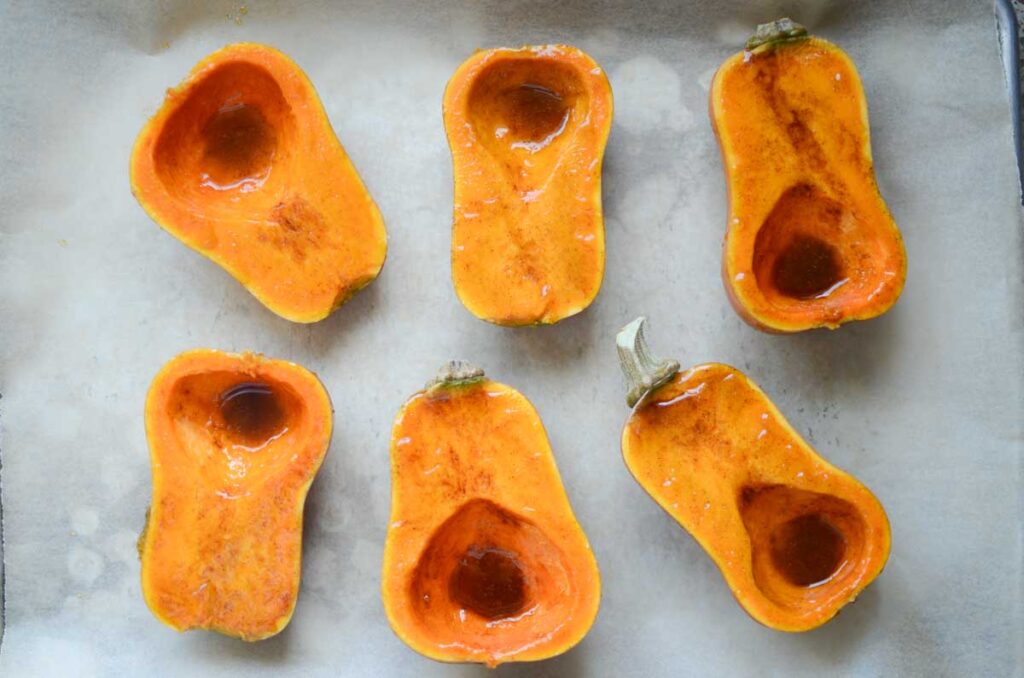 honeynut squash halves with curry flavored rub on a parchment lined baking sheet 